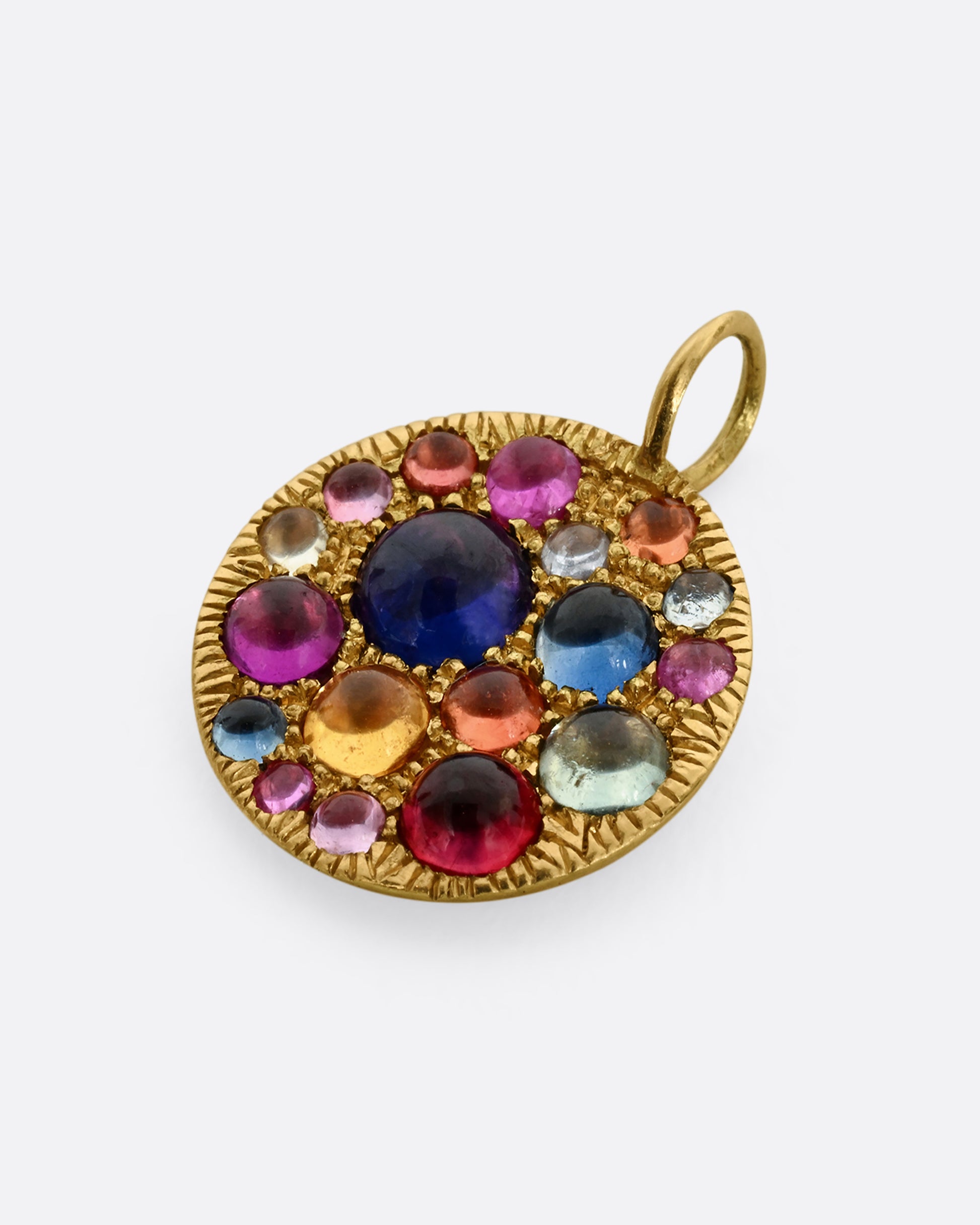 A yellow gold pendant with multicolor cabochon sapphires. View from the front, laying flat.