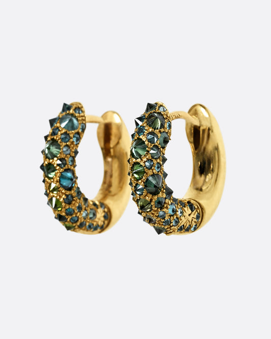 Inverted green diamonds set in yellow gold huggie hoops. Shown from the side.