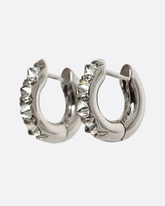 Inverted white diamonds set in platinum huggie hoops. Shown from the side.