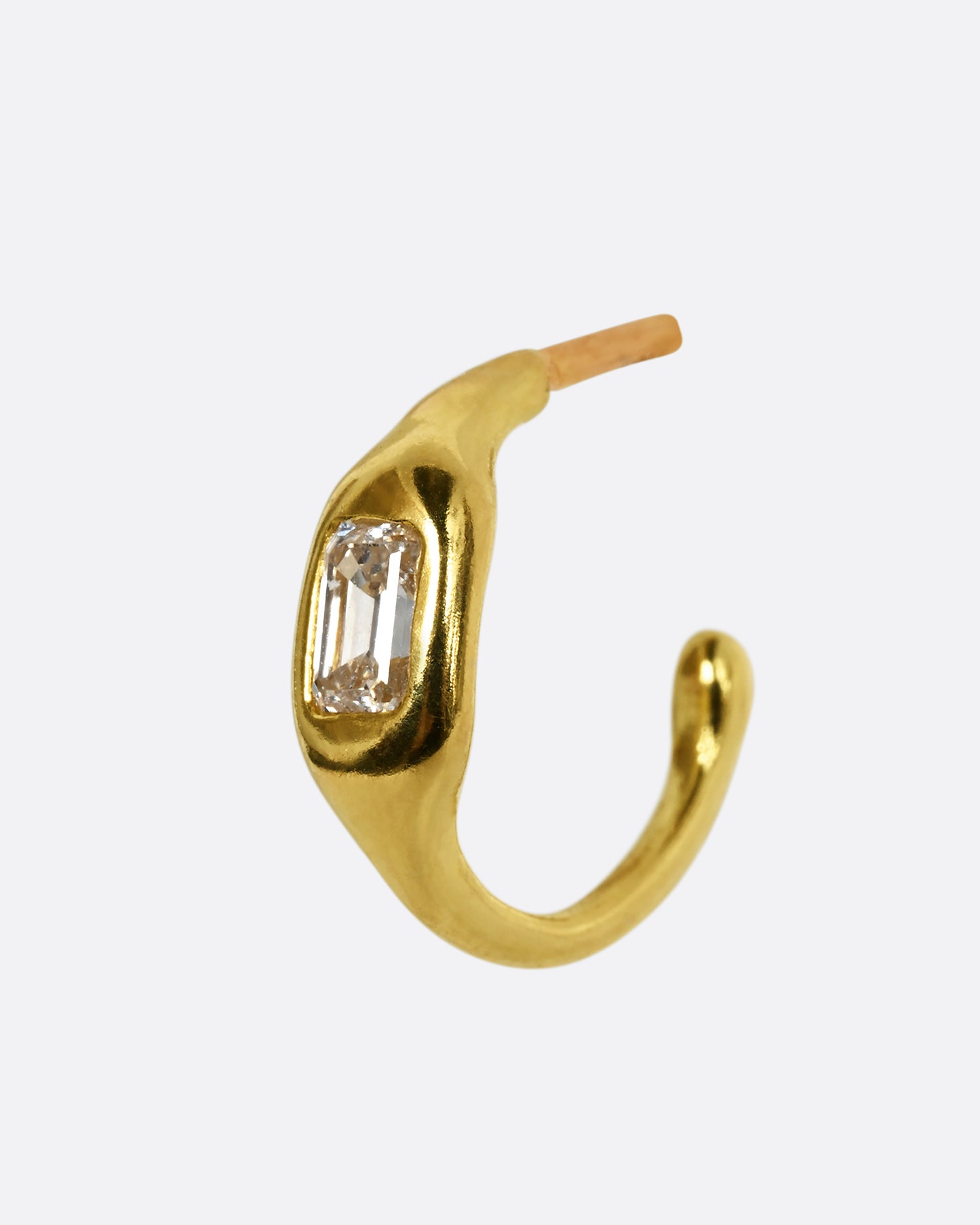 A yellow gold hoop with a single baguette diamond. Shown from the side.