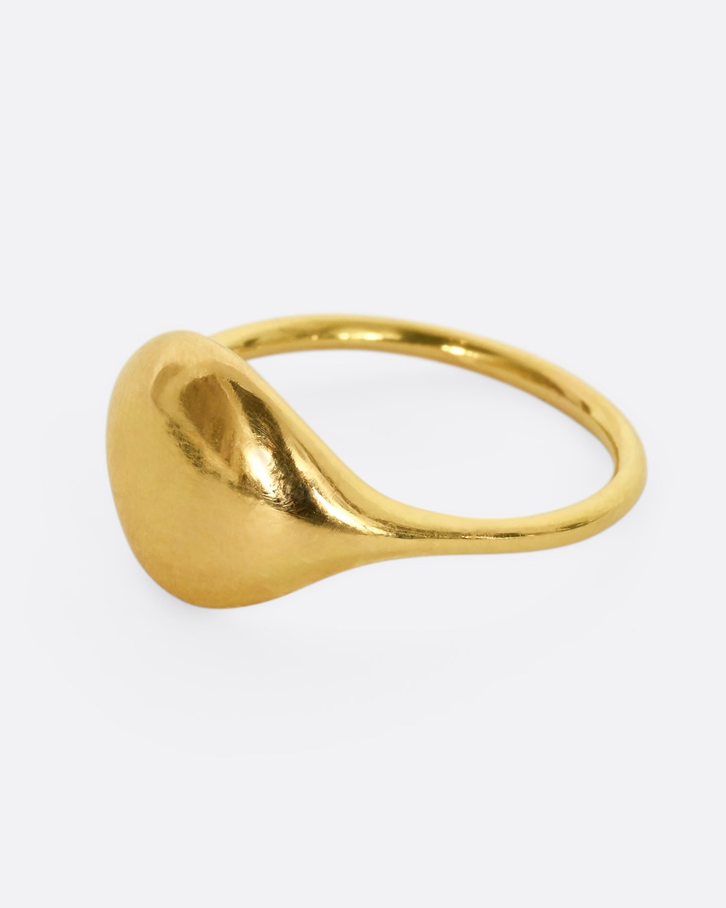 A yellow gold rounded signet ring. Shown from the side.