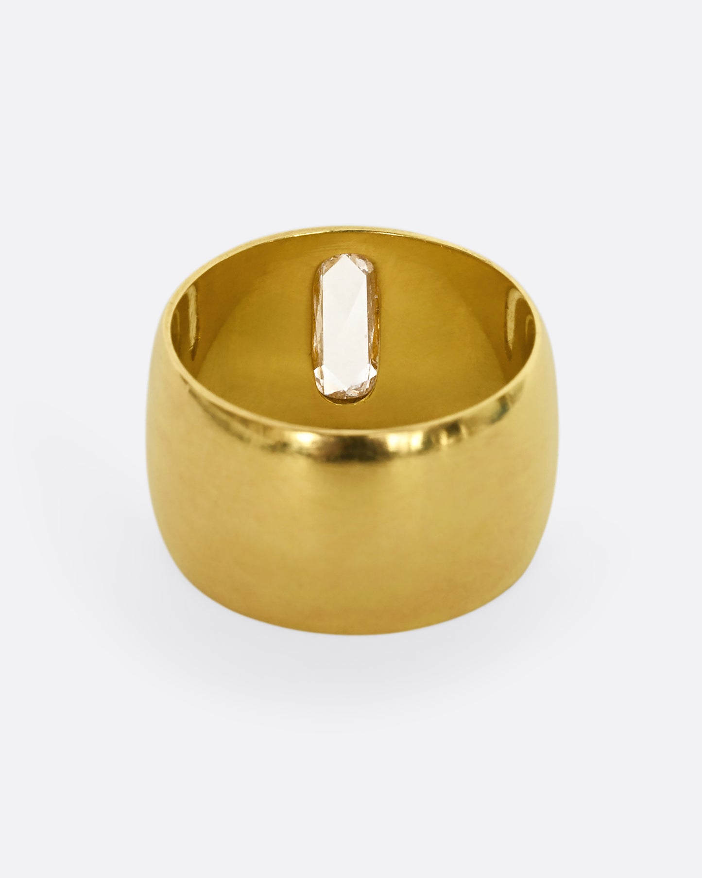 A yellow gold cigar band with an oval shaped diamond. Shown from the back.