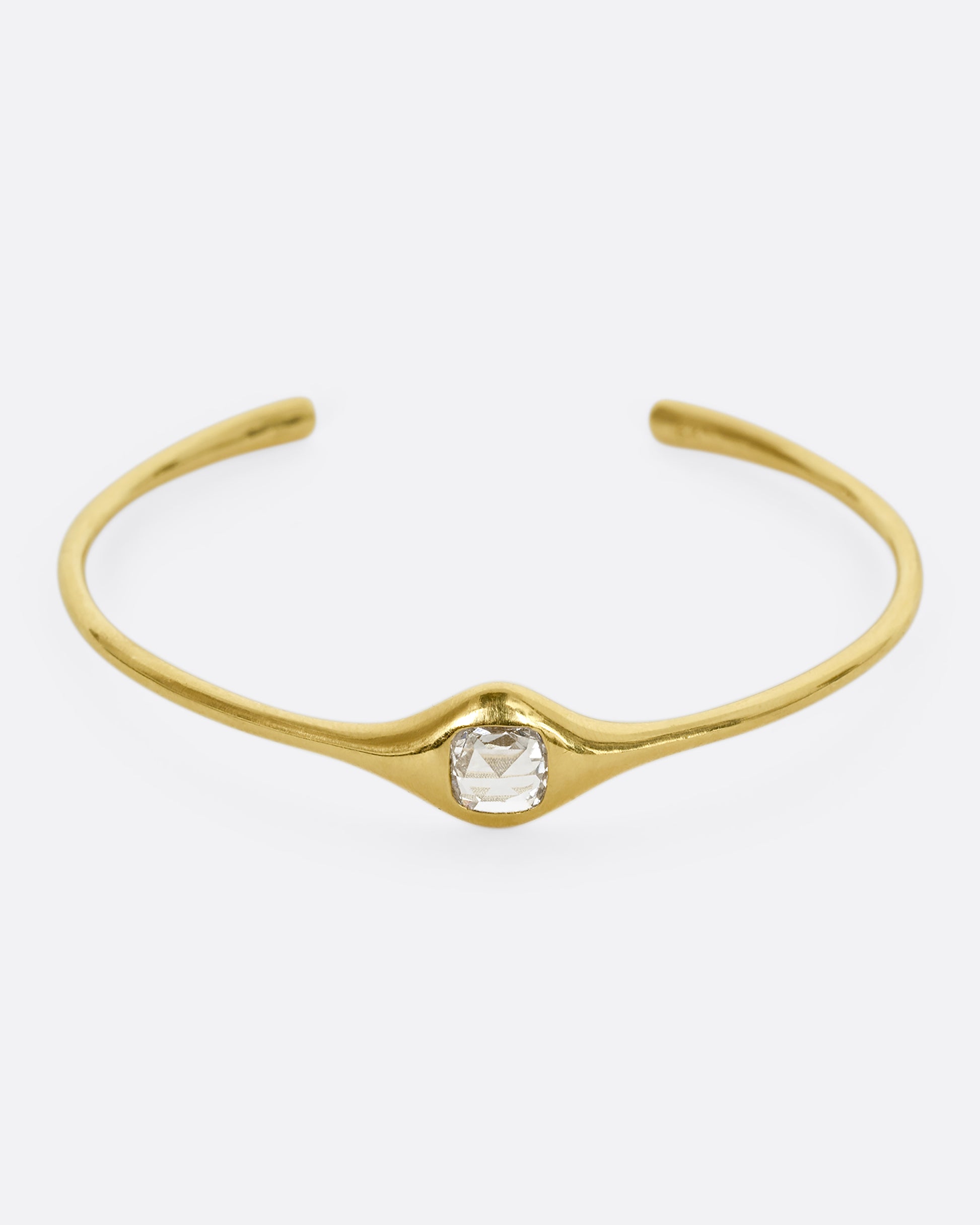 A yellow gold cuff bracelet with a rose cut cushion shaped diamond. Shown from the front.