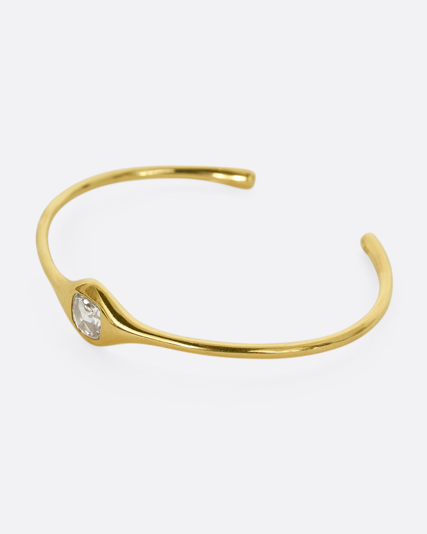 A yellow gold cuff bracelet with a rose cut cushion shaped diamond. Shown from the side.