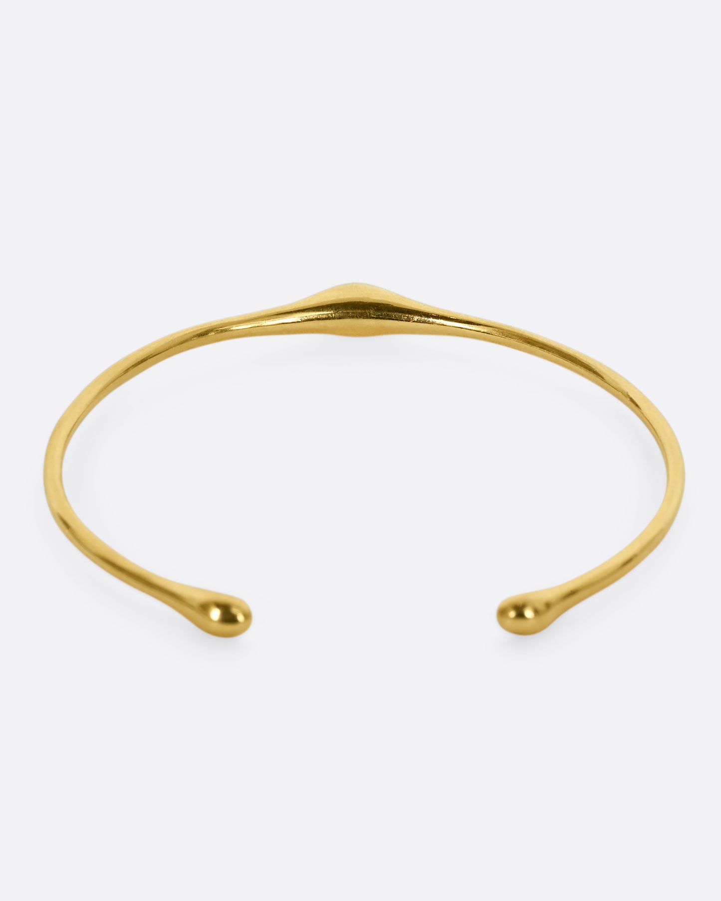 A yellow gold cuff bracelet with a bump. Shown from the back.