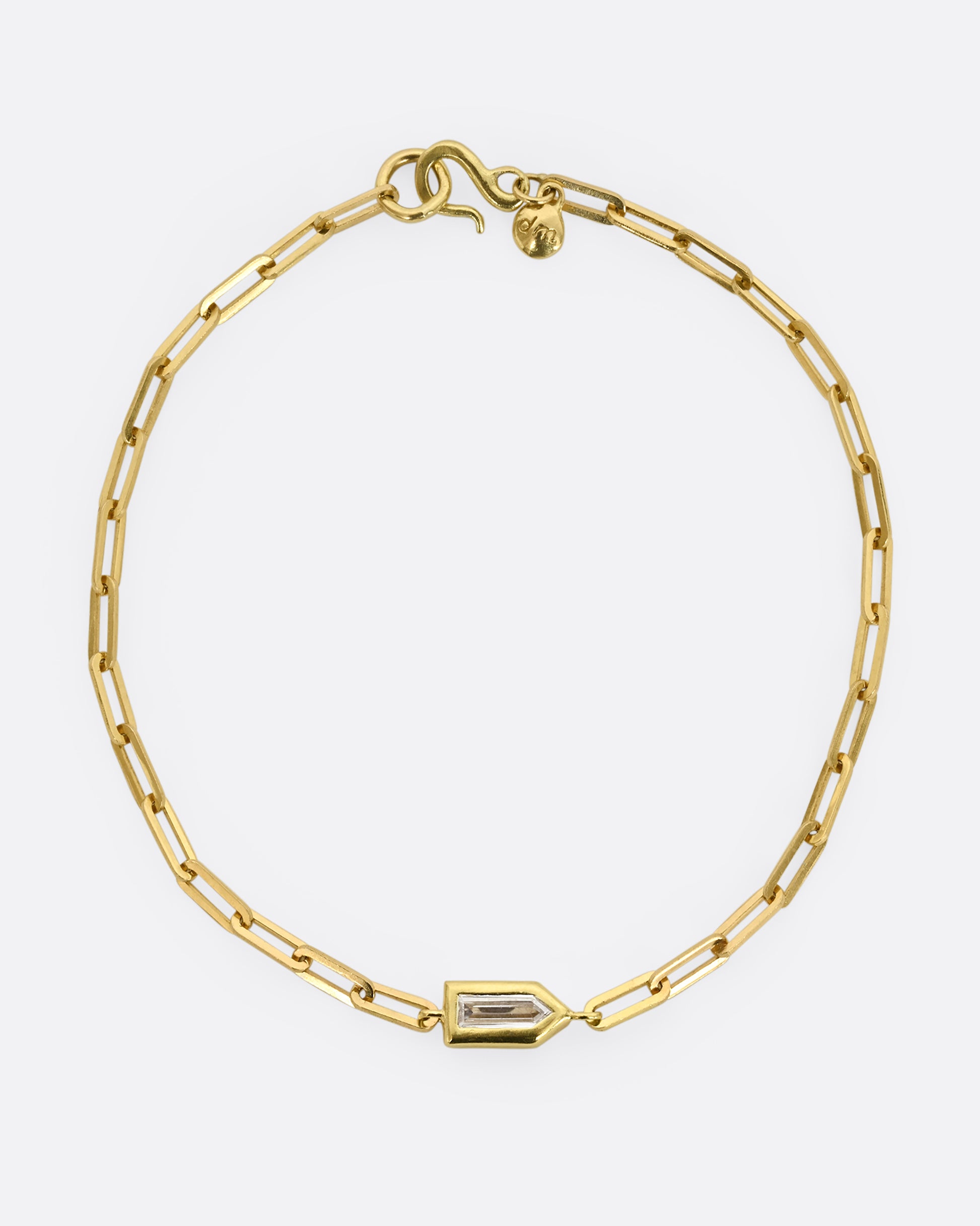 A yellow gold paperclip chain bracelet with a bullet shaped diamond channel. Shown closed, from above.