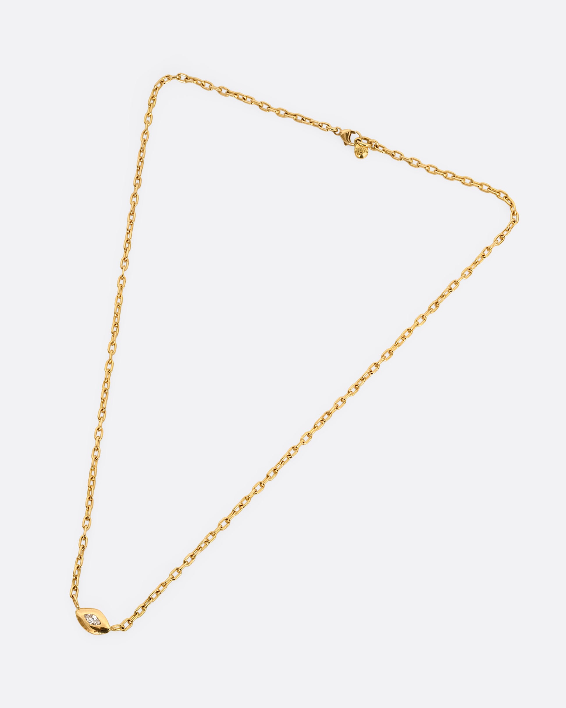 A yellow gold necklace with a marquis diamond pendant. Shown laying flat.