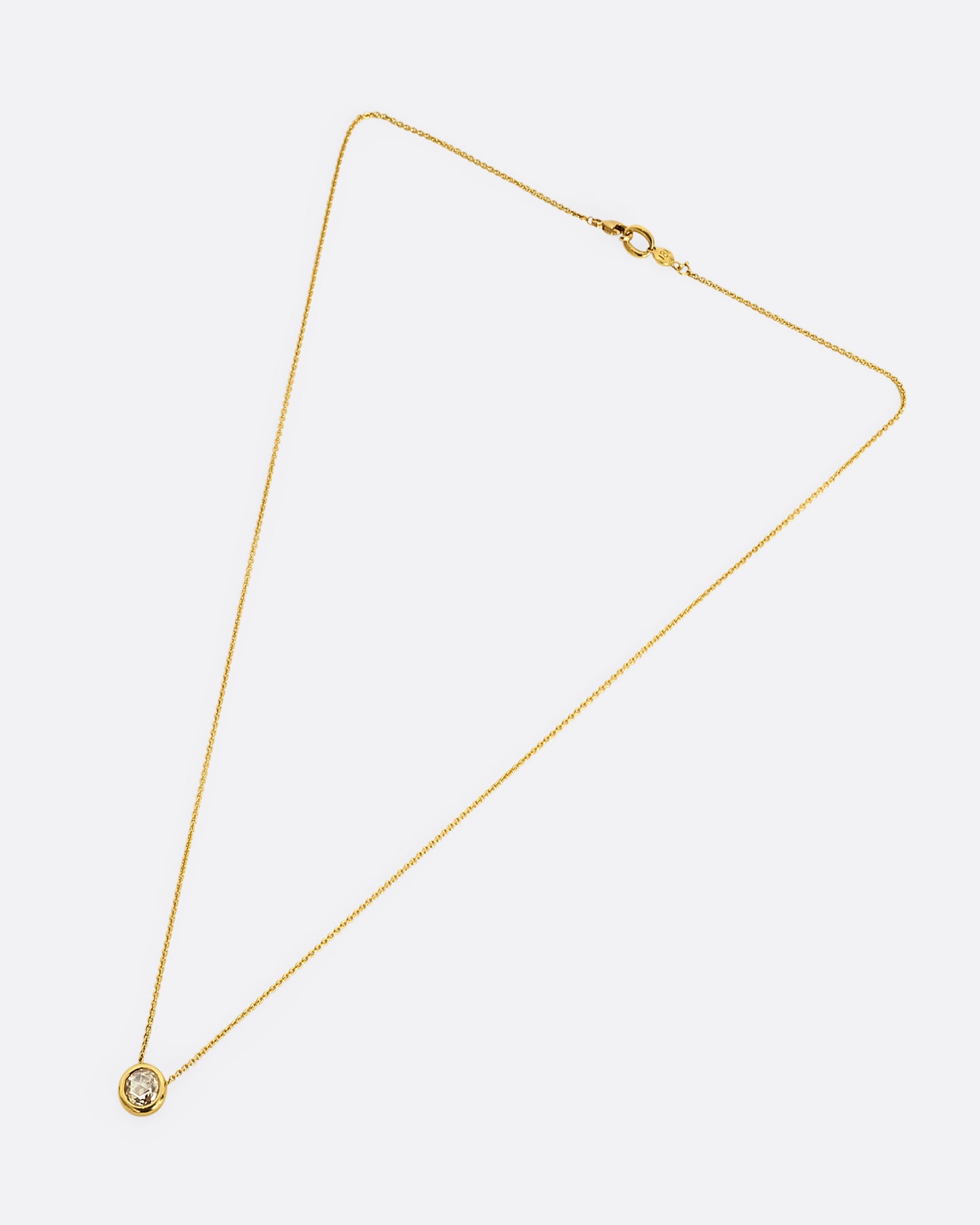 A yellow gold necklace with a circular shaped rose cut diamond. Shown laying flat.