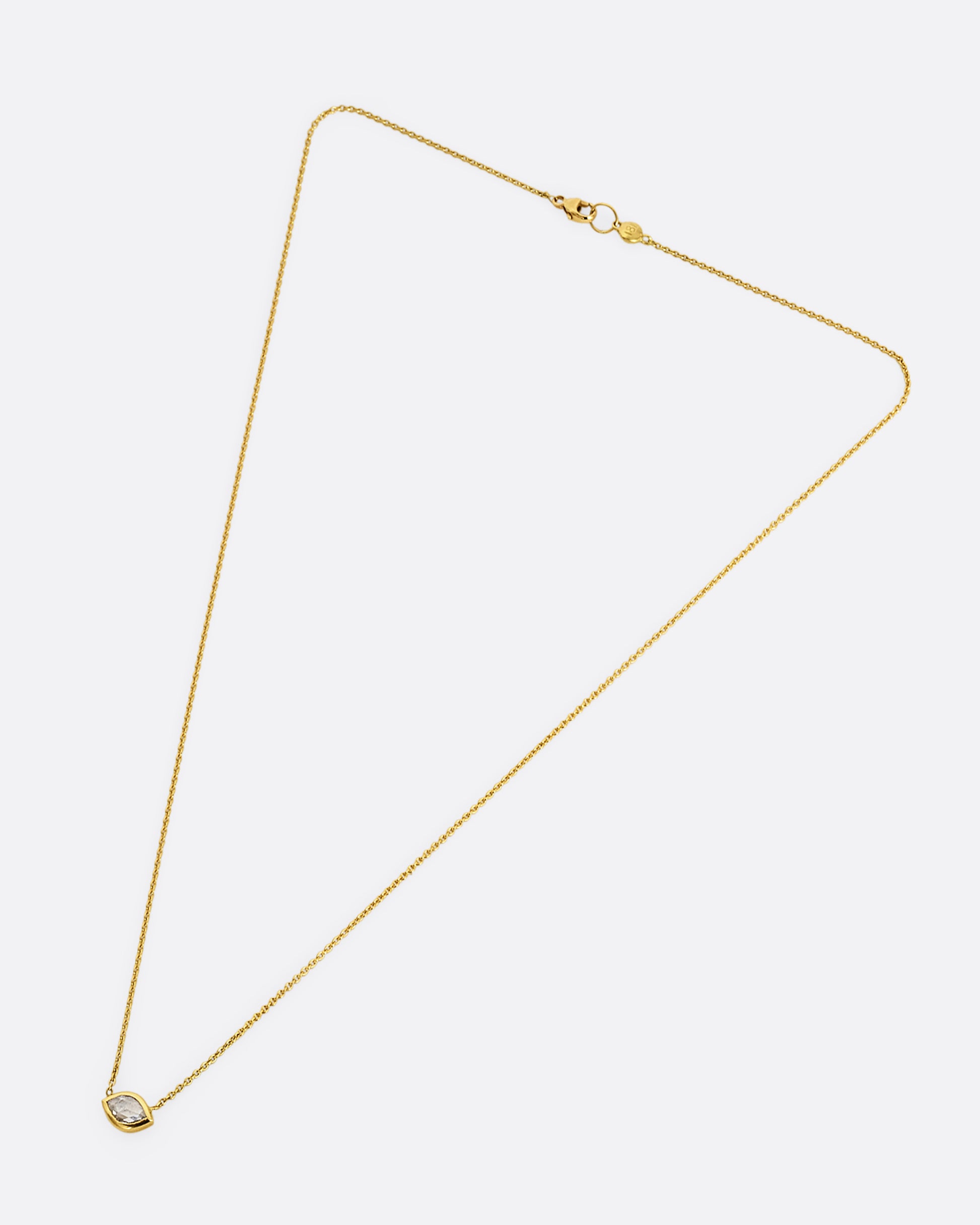 A yellow gold necklace with a  marquis shaped diamond. Shown laying flat.