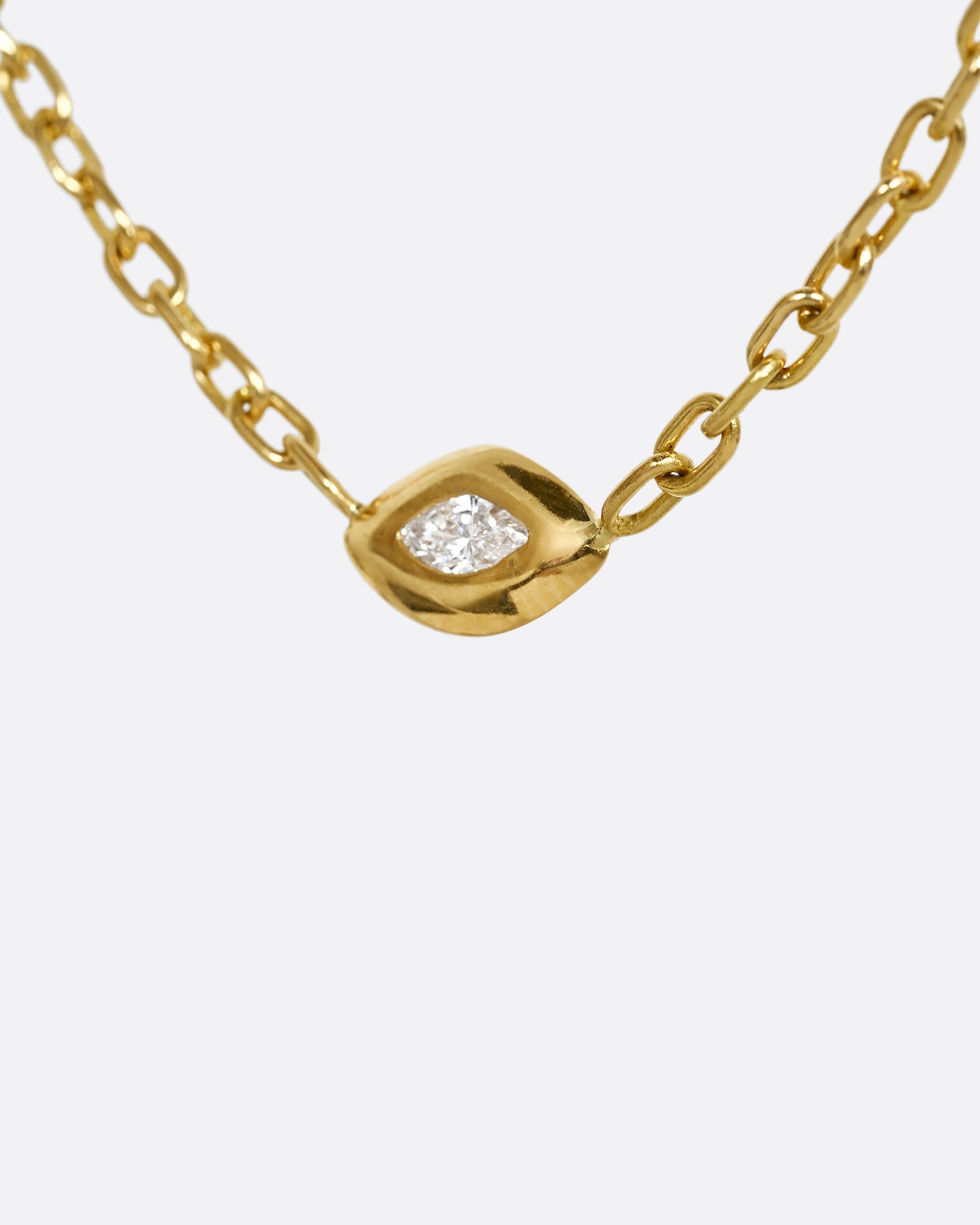 A yellow gold necklace with a marquis diamond pendant. Shown from the side.