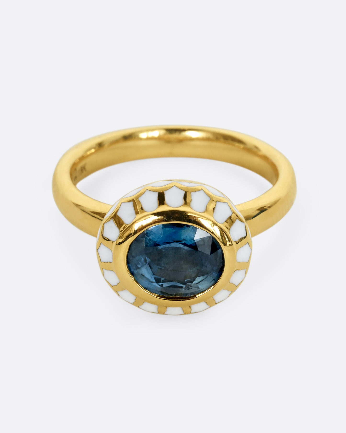 A yellow gold ring with a light blue sapphire and white enamel halo. Shown from the front, and slightly above.