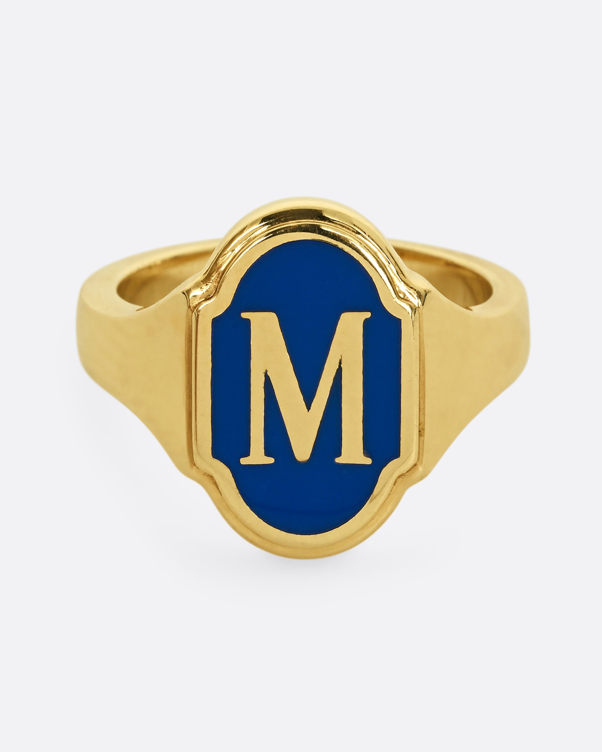 A yellow gold signet ring with blue enamel and the letter "M". Shown from the front.