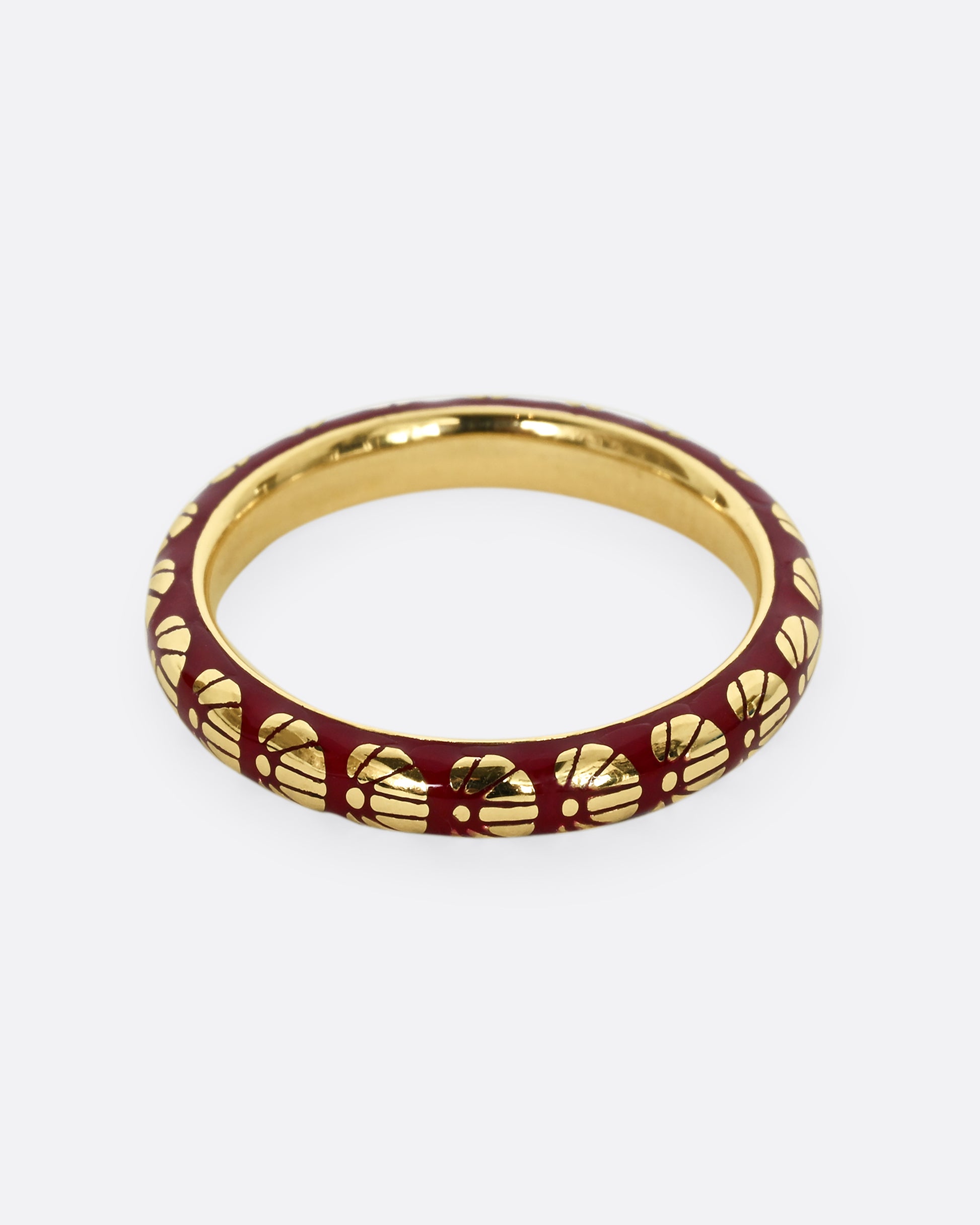 A yellow gold ring with burgundy enamel and a floral motif around the entire band.