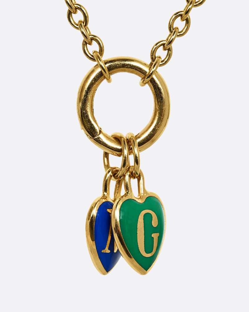A yellow gold cable chain necklace with a charm holder and two heart shaped charms- one blue with an M and one green with a G. Shown from the front.