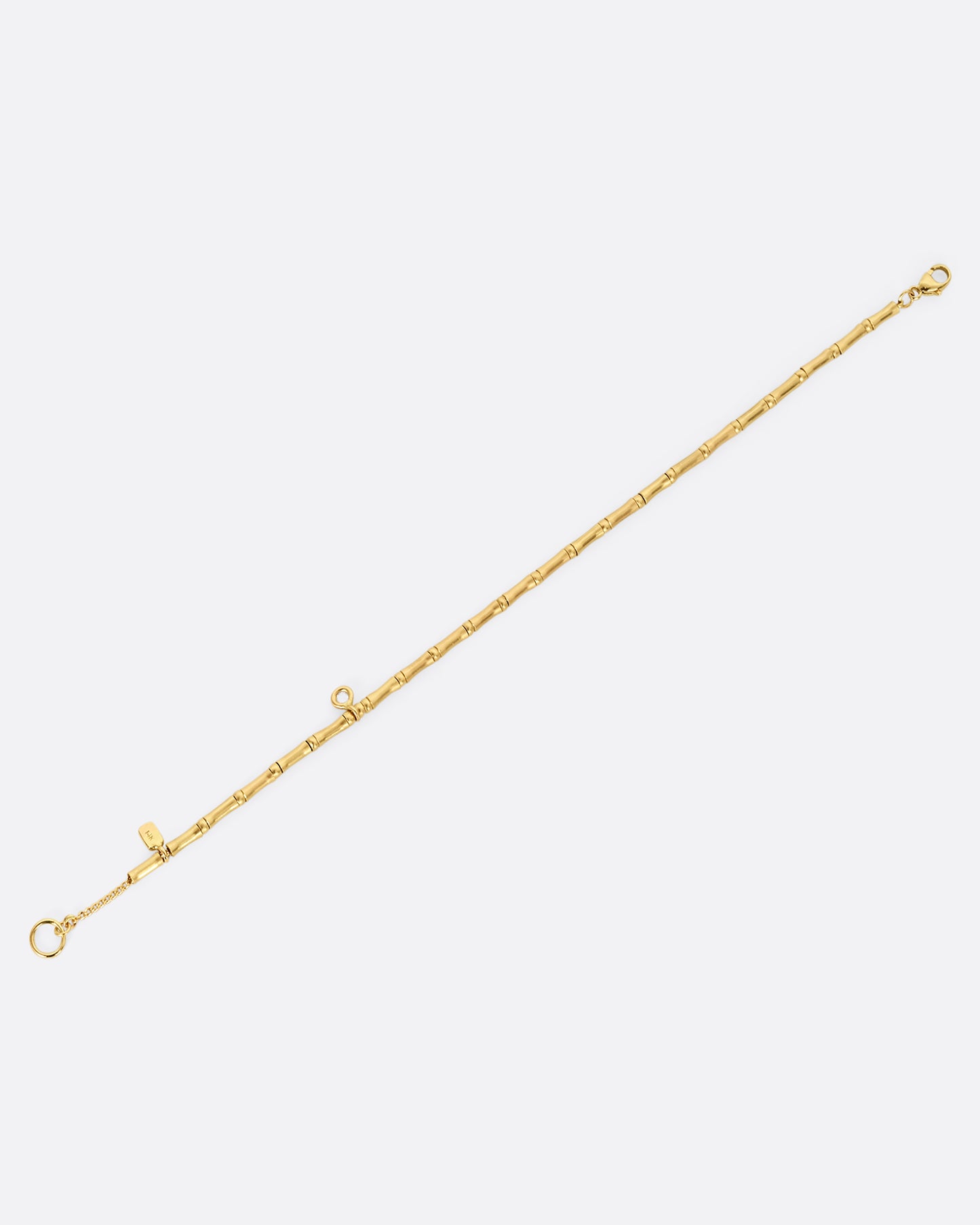 A yellow gold bracelet with tube beads and a single diamond. Shown laying flat.