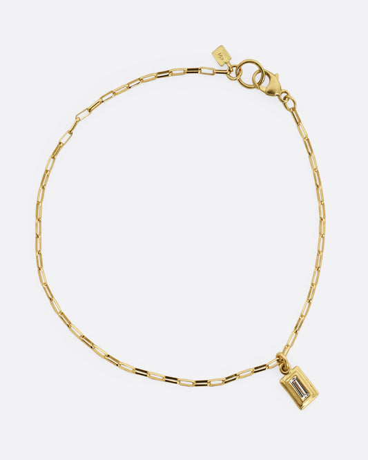 A yellow gold elongated rolo chain bracelet with a baguette diamond. Shown closed, from above. 