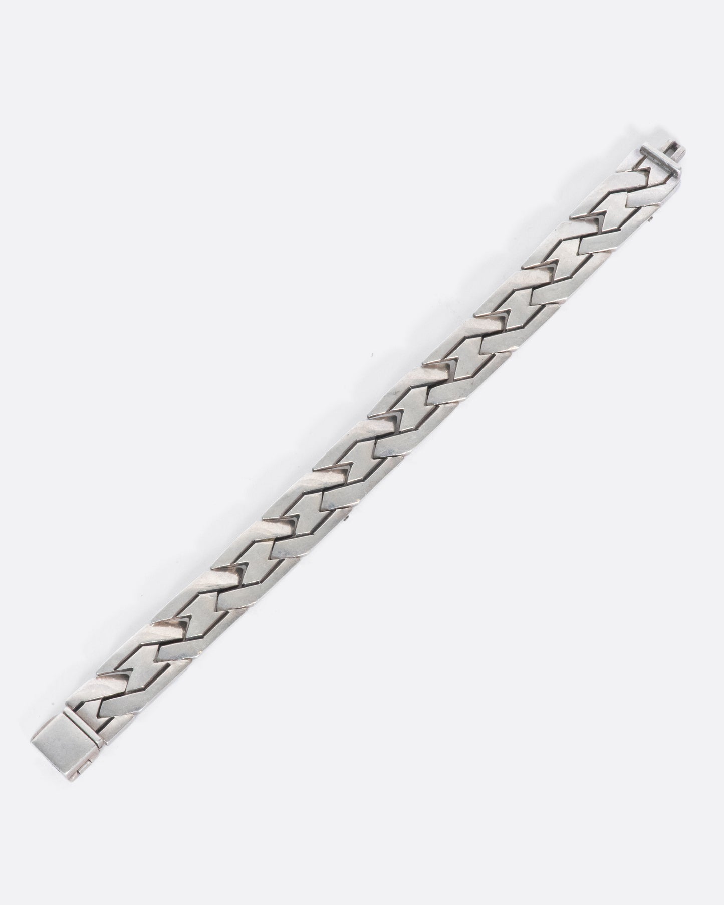 A vintage sterling silver flat chain bracelet with a woven-link design. The large, flat links reflect light making this piece especially eye-catching.