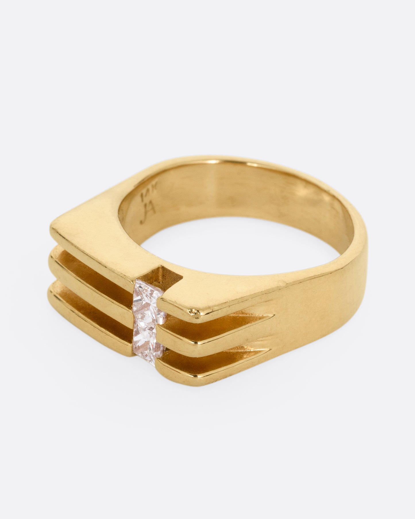 A yellow gold ring with linear channels and two princess cut diamonds, shown from the side. 