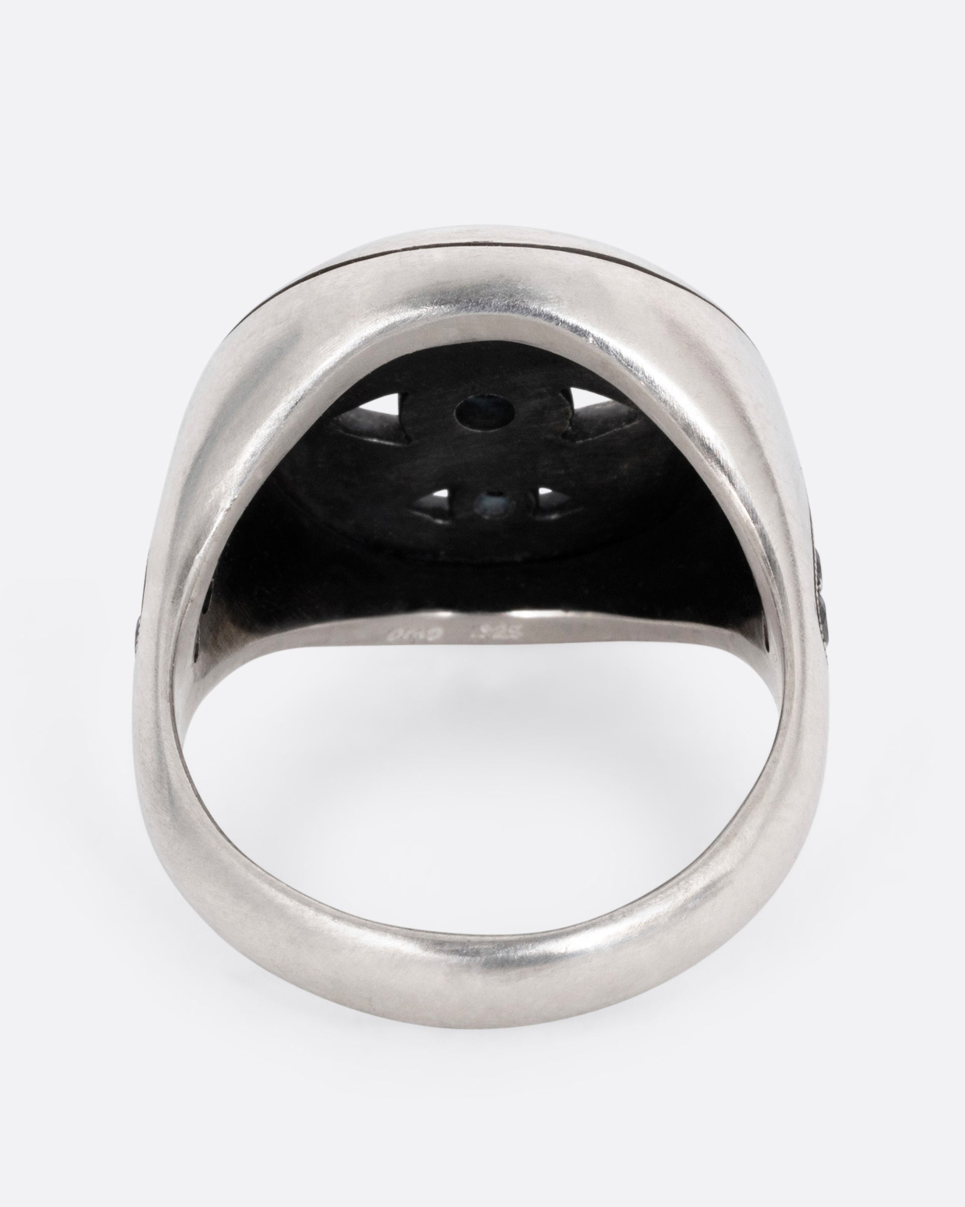 A silver ring with three eyes with black diamond centers, shown from the back.