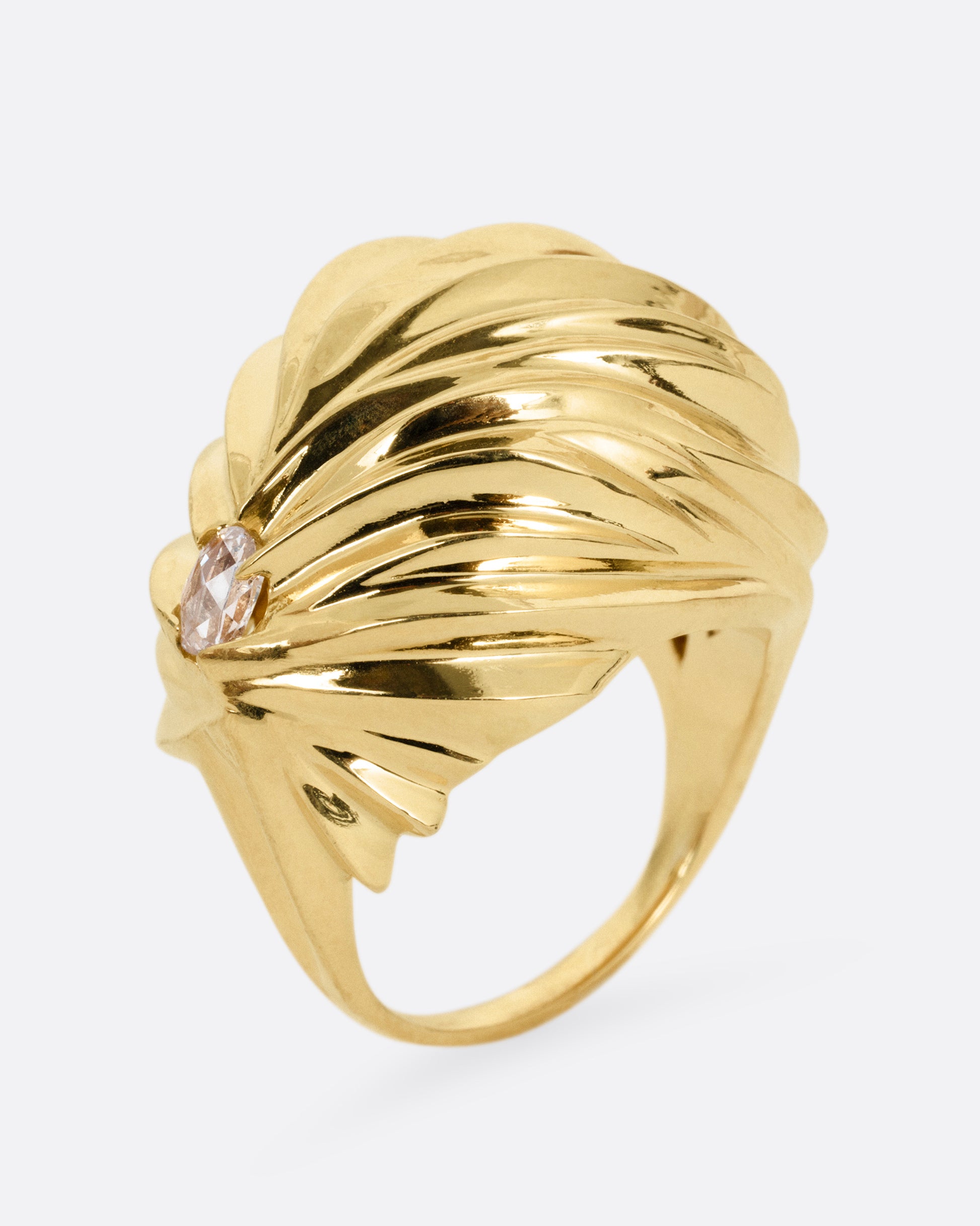 A yellow gold textural dome ring with a rose cut diamond, shown standing up from the side.