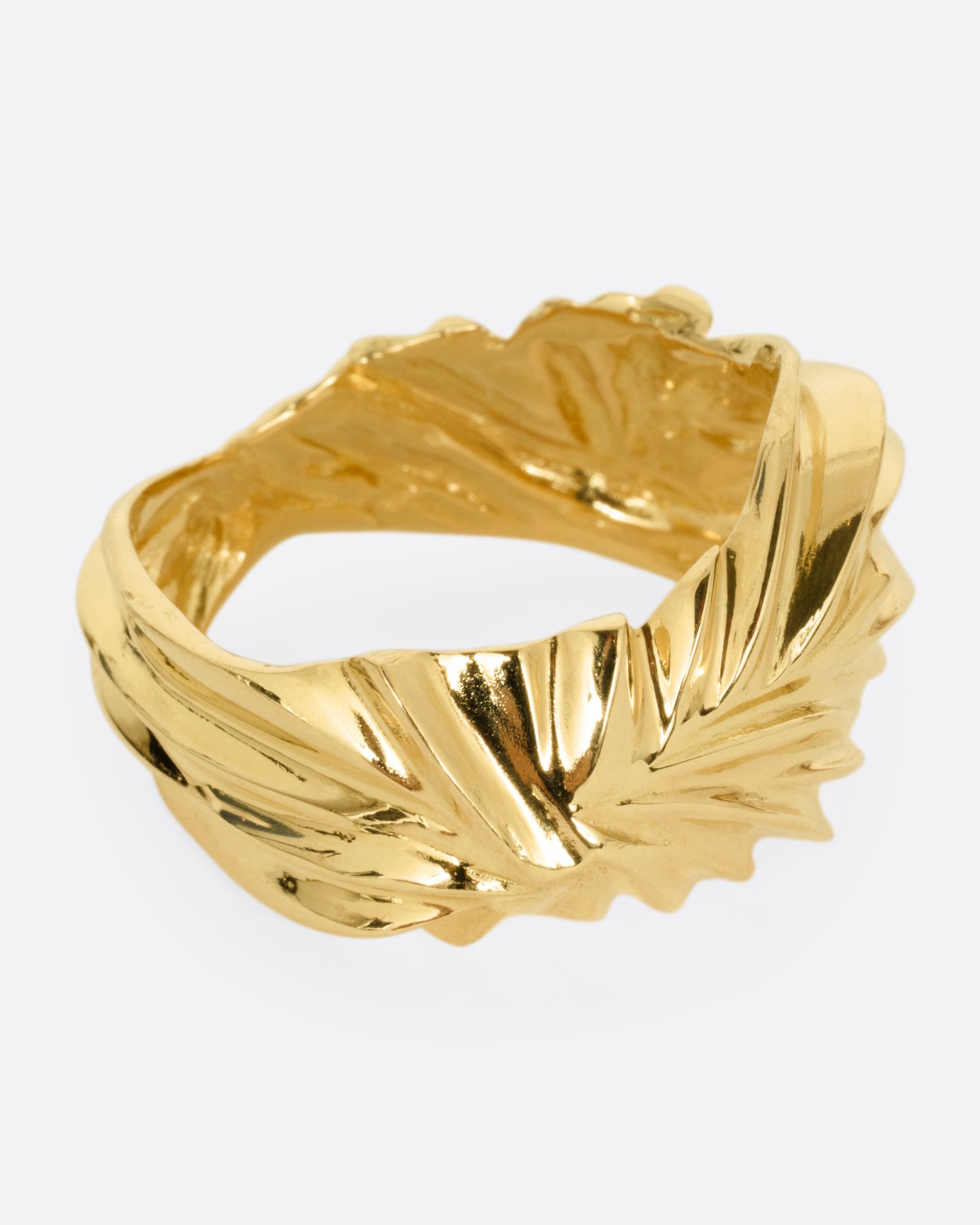 A yellow gold ring with wavy and chevron textures, shown from the side.