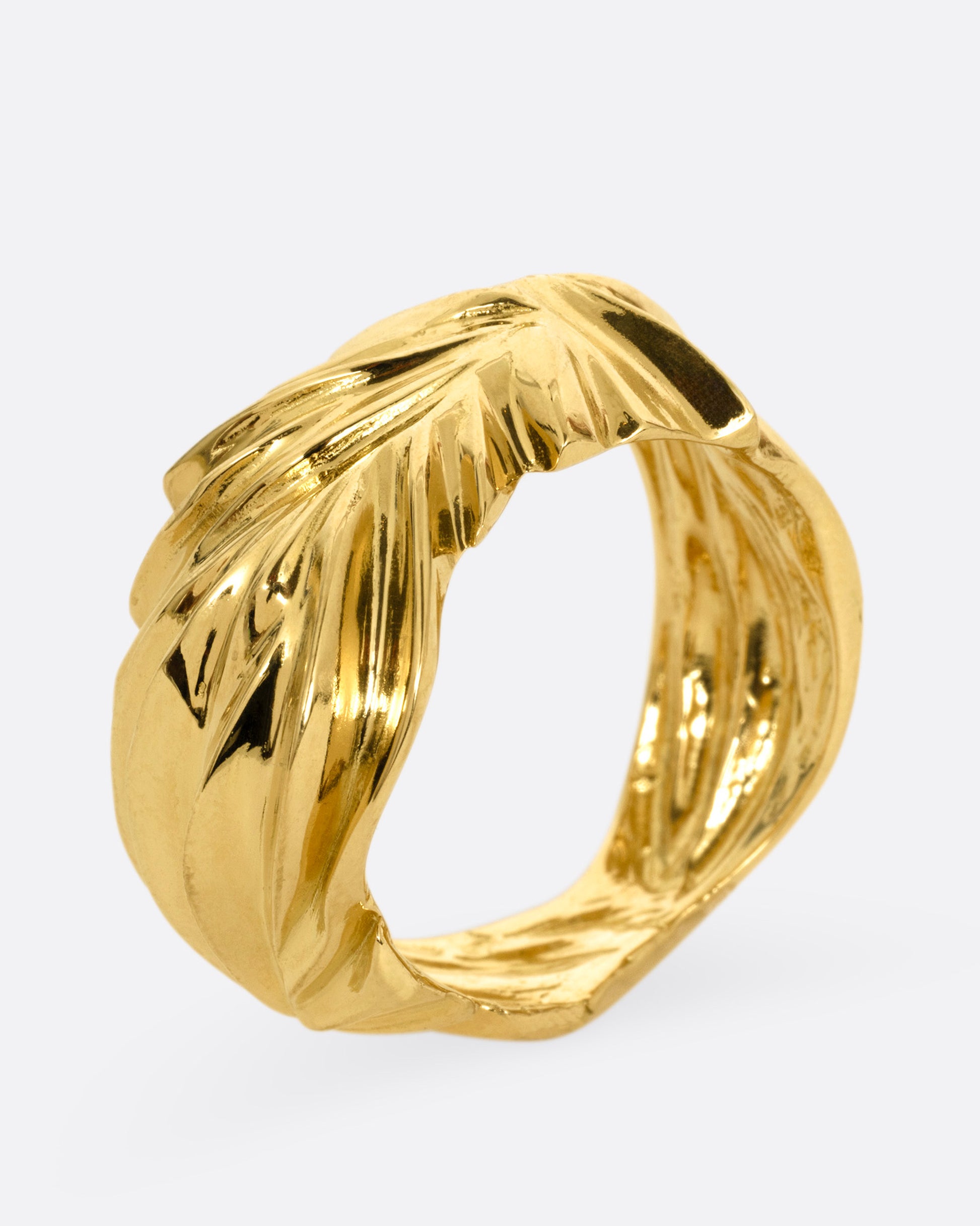 A yellow gold ring with wavy and chevron textures, shown from the side standing up.
