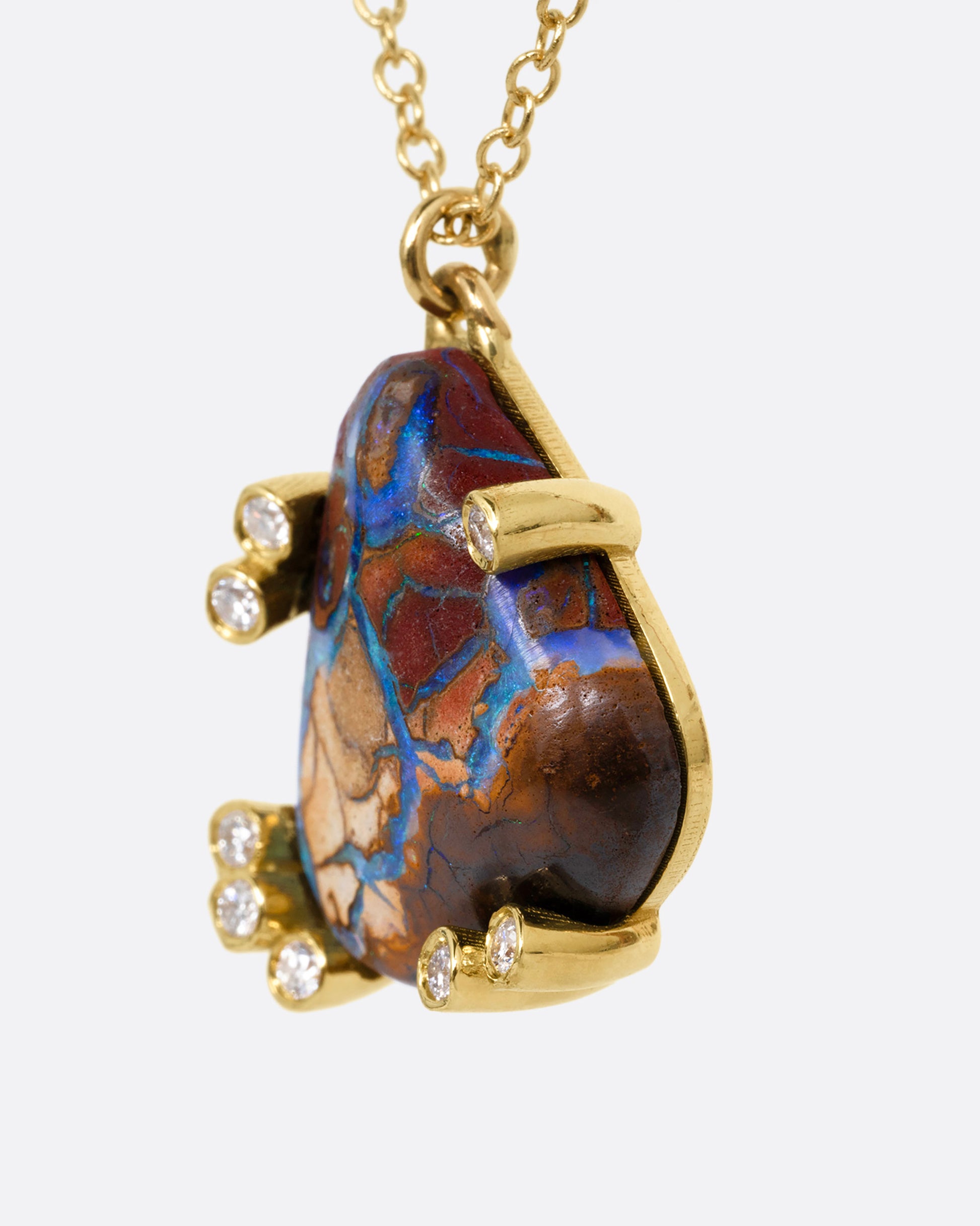 A yellow gold cable chain necklace with a free-form boulder opal and diamond anemones. Shown from the side.