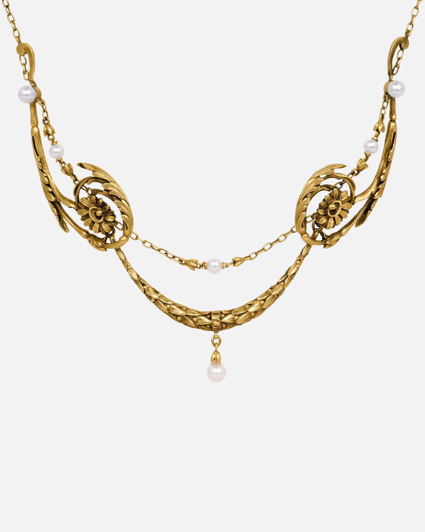 A yellow gold necklace with pearls and flower details, shown from the front.