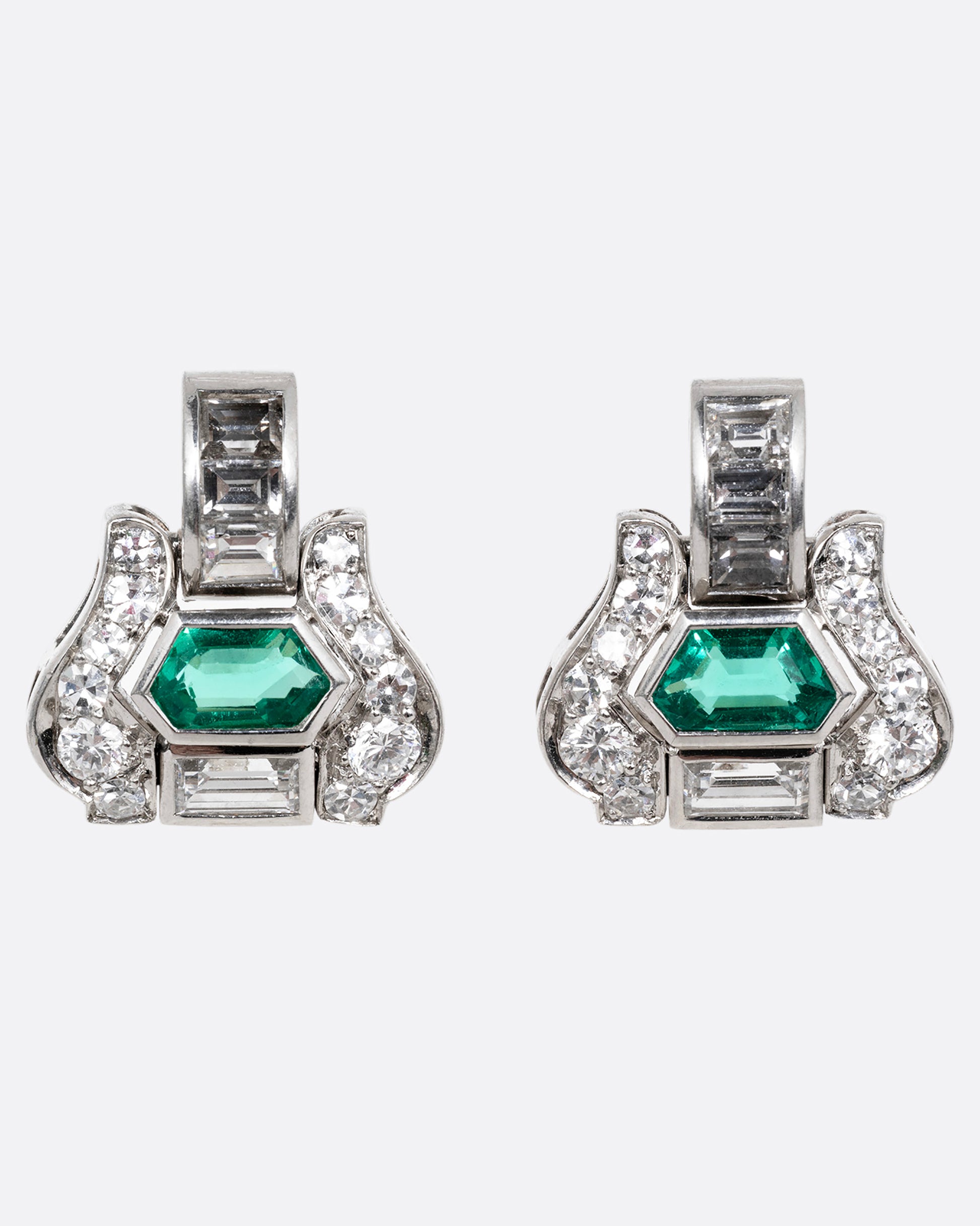 A pair of platinum earrings with emeralds and diamonds, shown from the front.