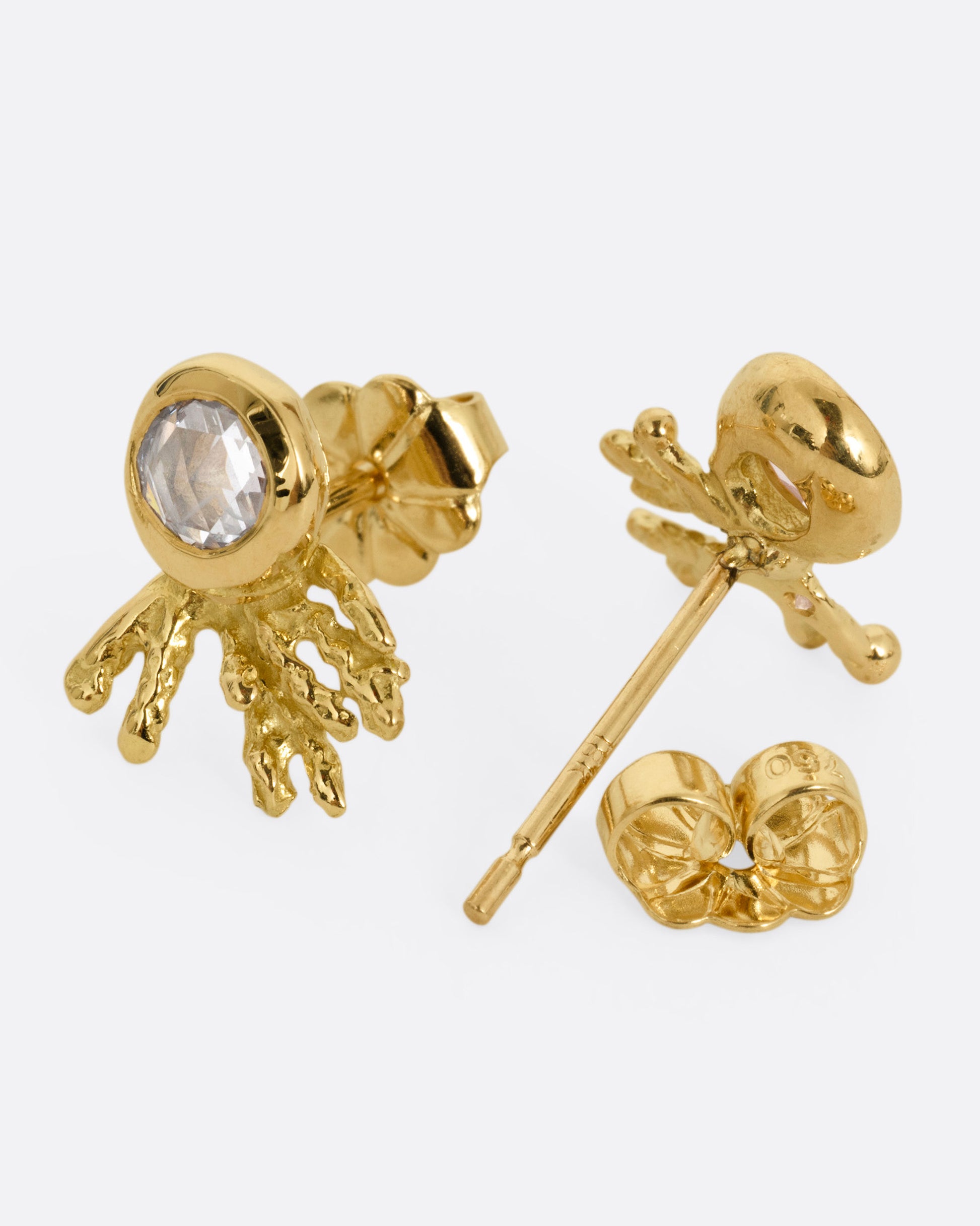 A pair of yellow gold studs earrings with rose cut diamonds and yellow gold comet-like tails. One earring is shown from the front, the other is shown ope from the back.