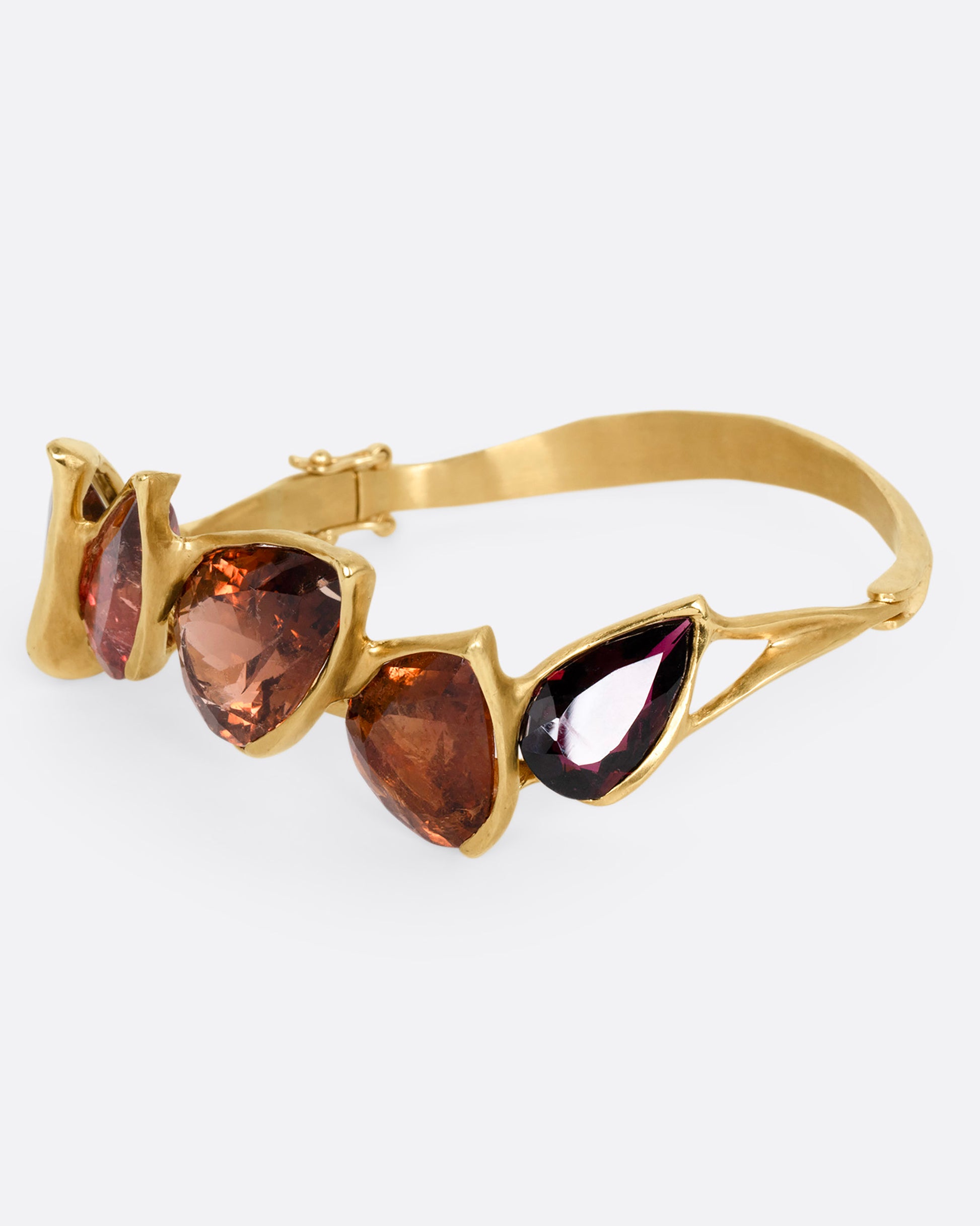 A yellow gold bracelet with five teardrop shaped tourmalines, shown from the side.