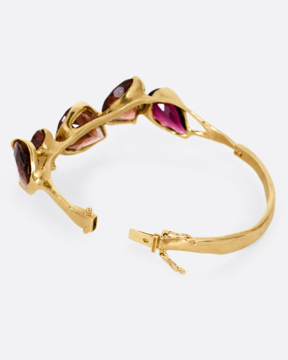 A yellow gold bracelet with five teardrop shaped tourmalines, shown from the back open.