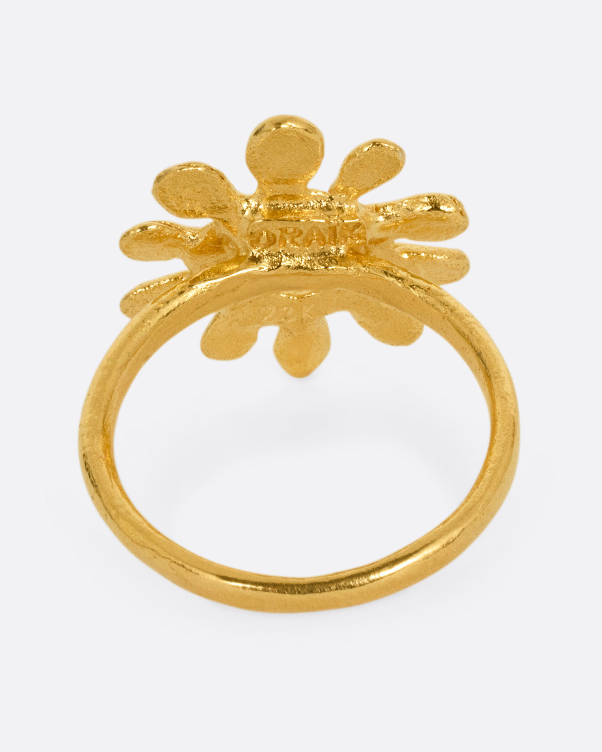 A yellow gold sun shaped ring with red stone eyes, shown from the back.