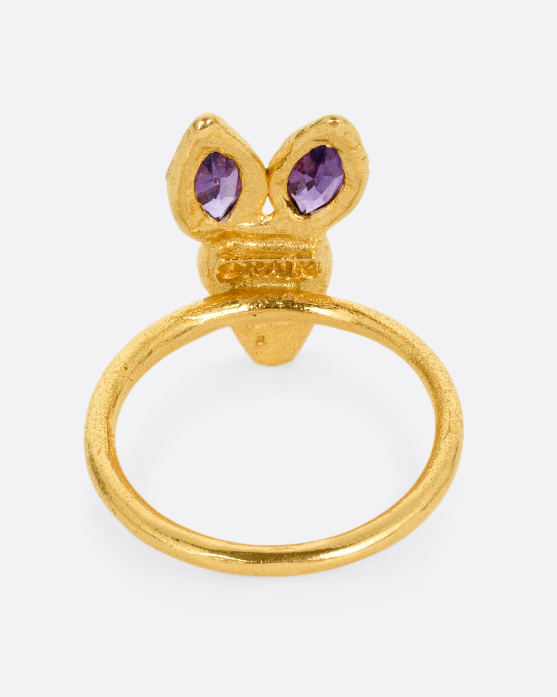 A yellow gold ring with a rabbit face with amethyst ears and tourmaline eyes. Shown from the back.