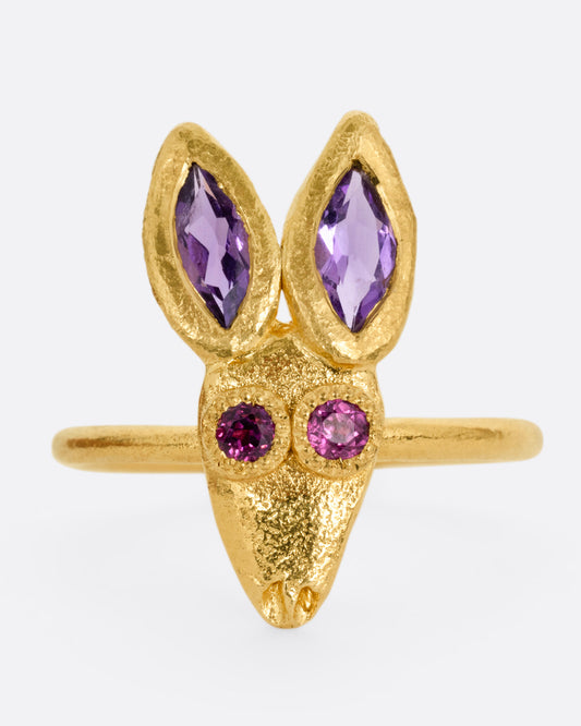A yellow gold ring with a rabbit face with amethyst ears and tourmaline eyes. Shown from the front.