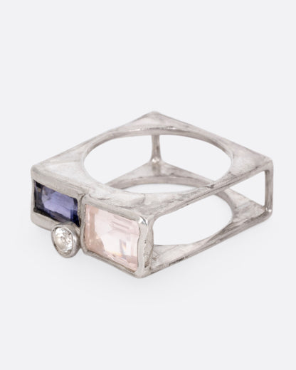 A silver square cage ring with a quartz, iolite, and topaz, shown from the side.