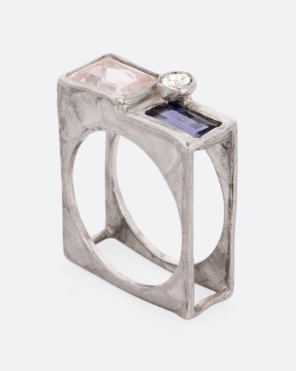 A silver square cage ring with a quartz, iolite, and topaz, shown standing up from the side.