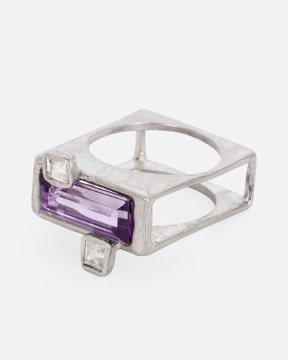 A silver square ring with an amethyst baguette and two square topaz, shown from the side.