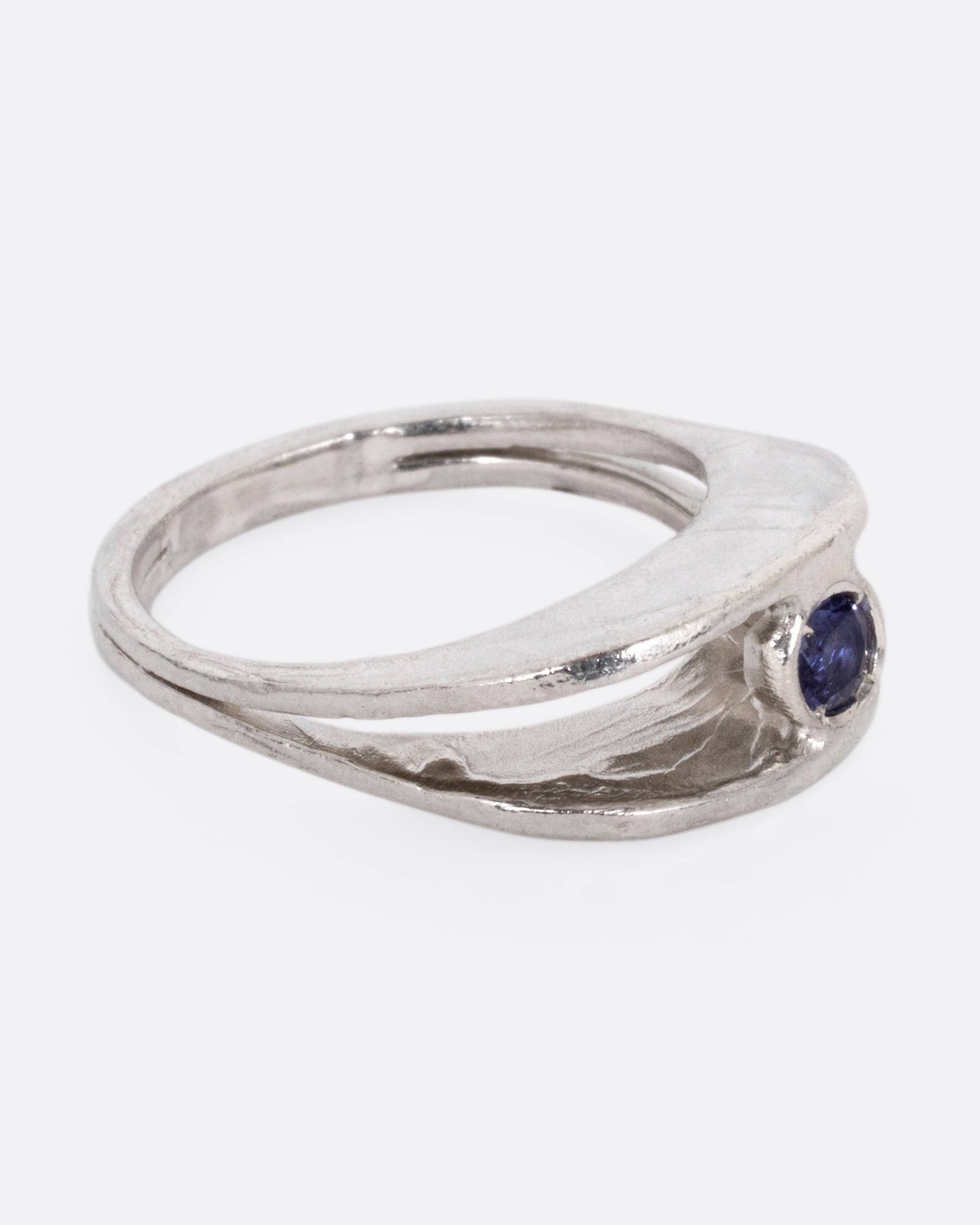 A silver ring with a split shank and a center iolite, shown from the side.