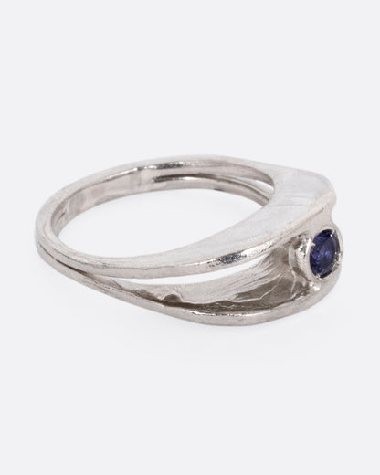A silver ring with a split shank and a center iolite, shown from the side.