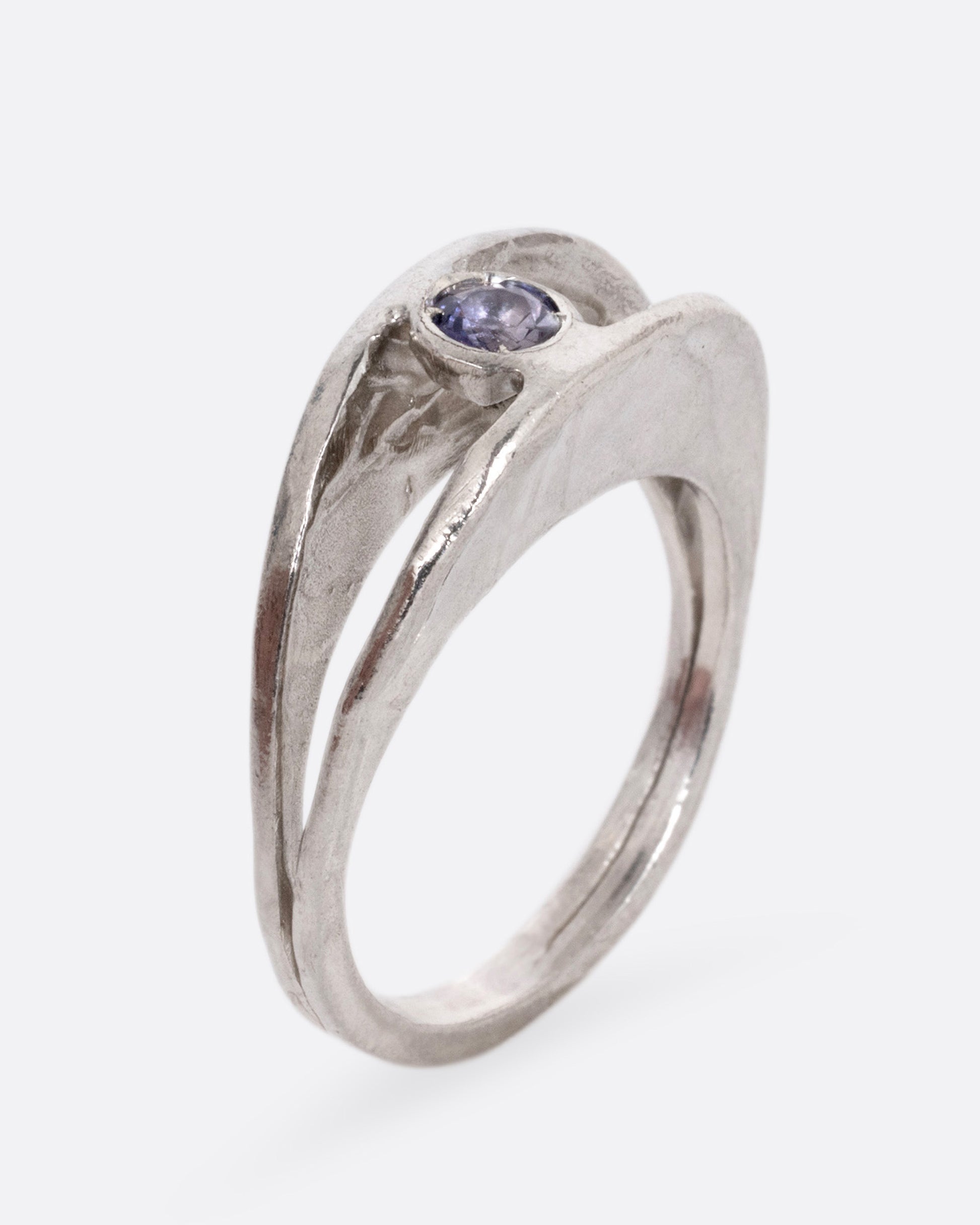 A silver ring with a split shank and a center iolite, shown from the side standing up.