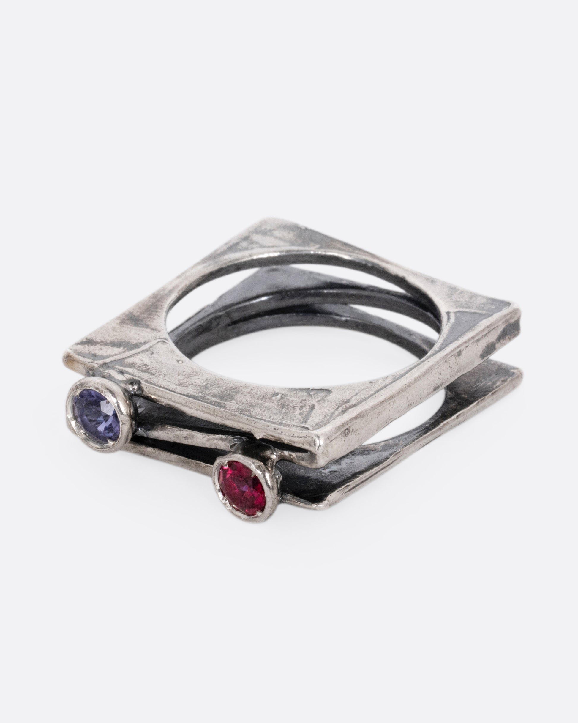 A silver stacked square ring with a blue sapphire and a pink sapphire shown from the side.