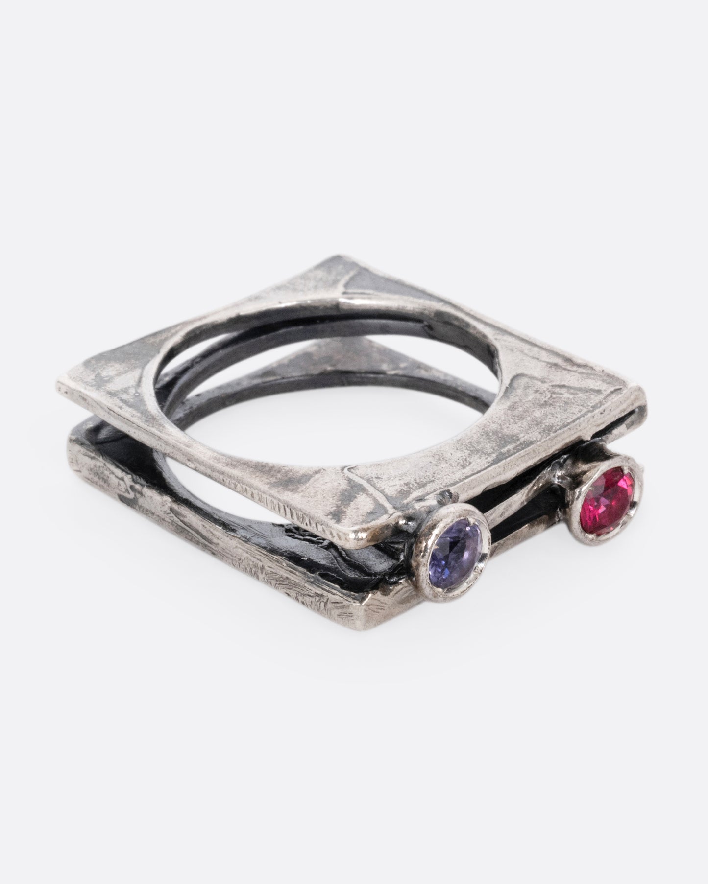 A silver stacked square ring with a blue sapphire and a pink sapphire shown from the side.