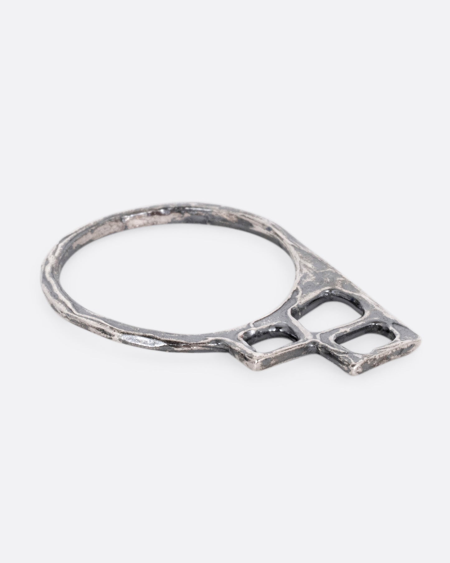 A silver ring with trio of stacked open windows, shown lying flat.