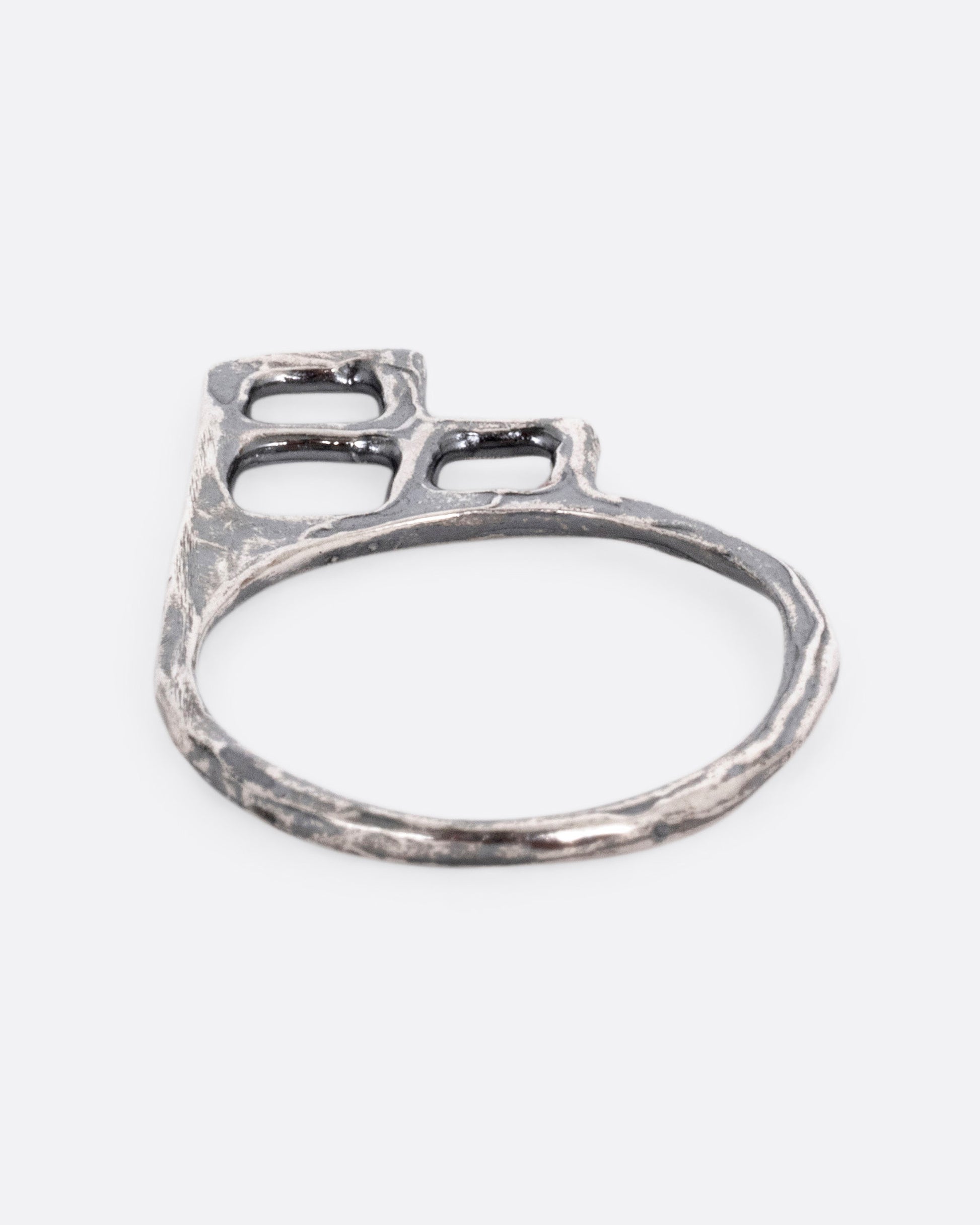 A silver ring with trio of stacked open windows, shown lying flat.