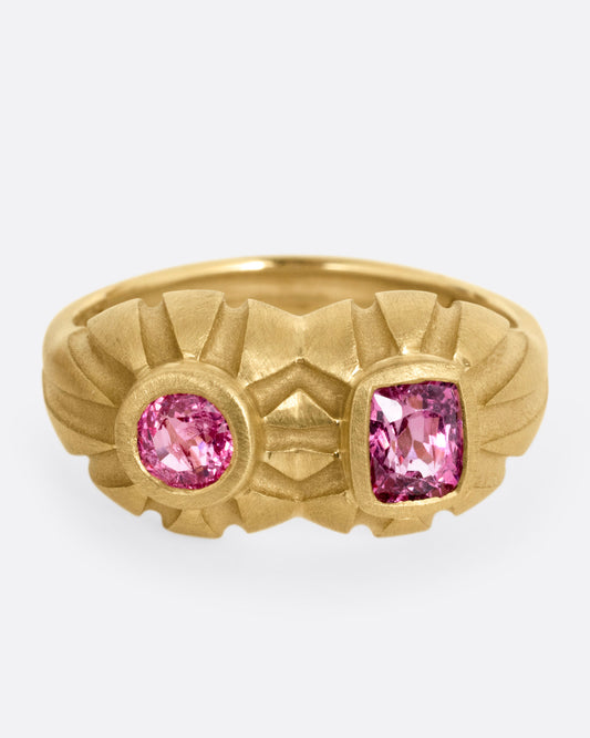 A yellow gold dimensional domed ring with two pink spinels, one round and one cushion cut, shown from the front.