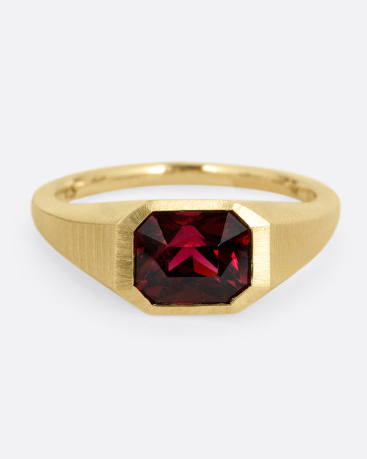 A yellow gold signet ring with a garnet, shown from the front.