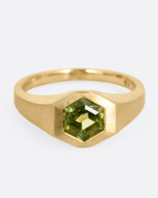 A yellow gold ring with a green hexagonal tourmaline, shown from the front.