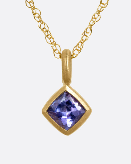 A yellow gold necklace with a tanzanite pendant, shown from the front.