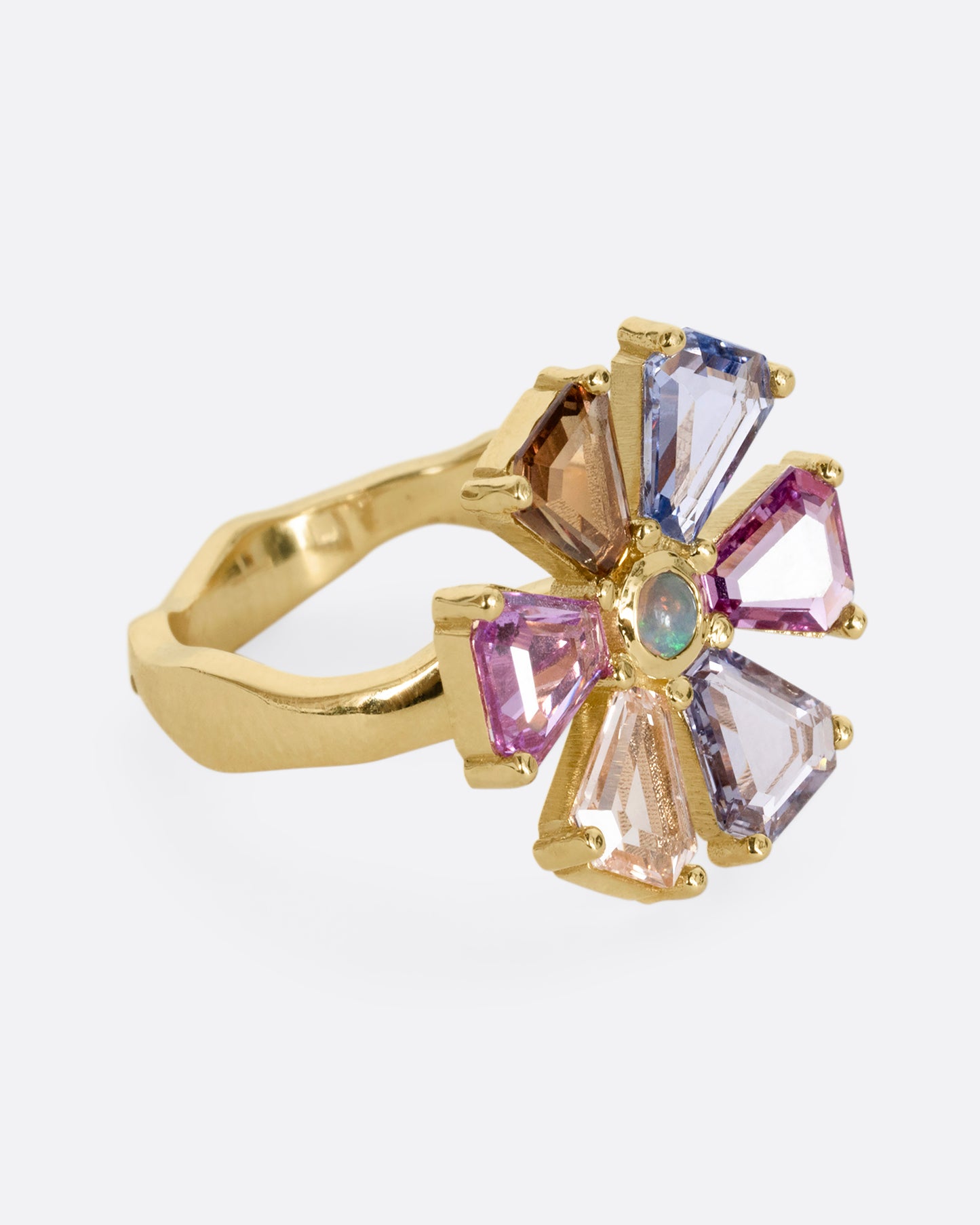 A yellow gold ring with a spinning flower made of multicolor sapphires. Shown from the side.